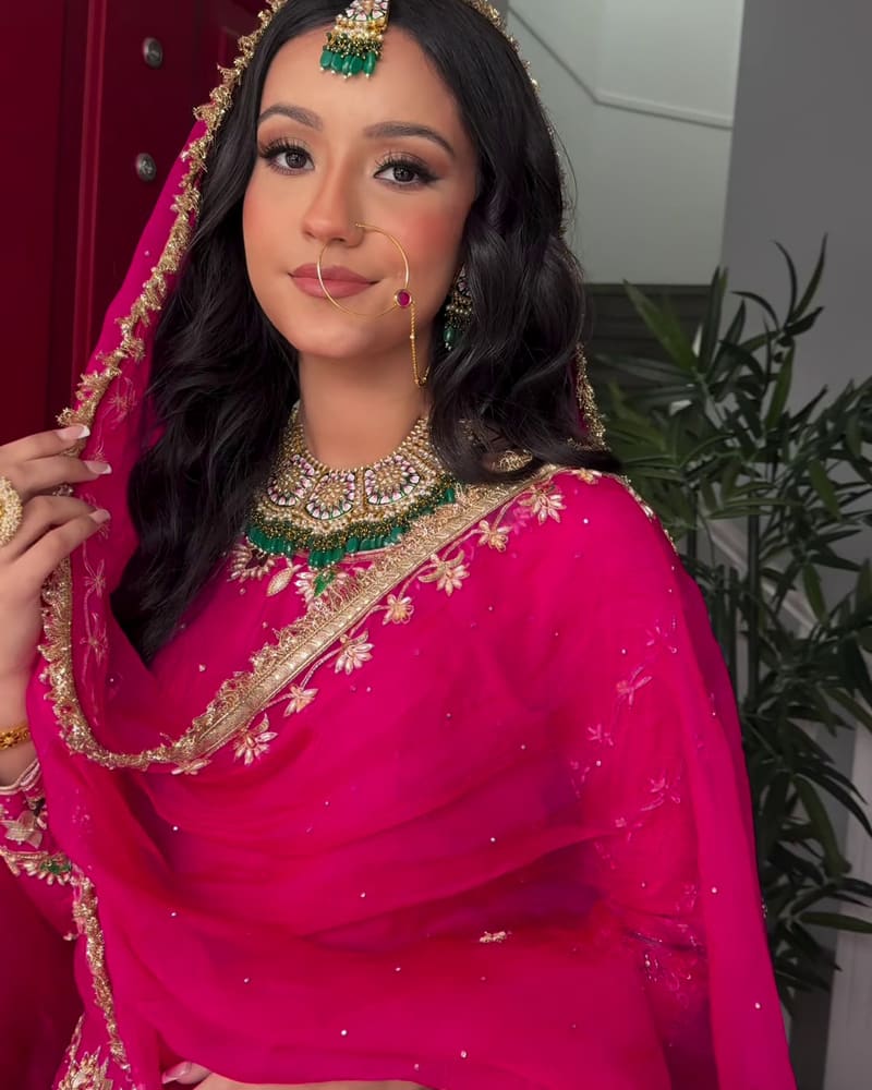 Bride in fuchsia with the dupatta draped over her head, smiling
