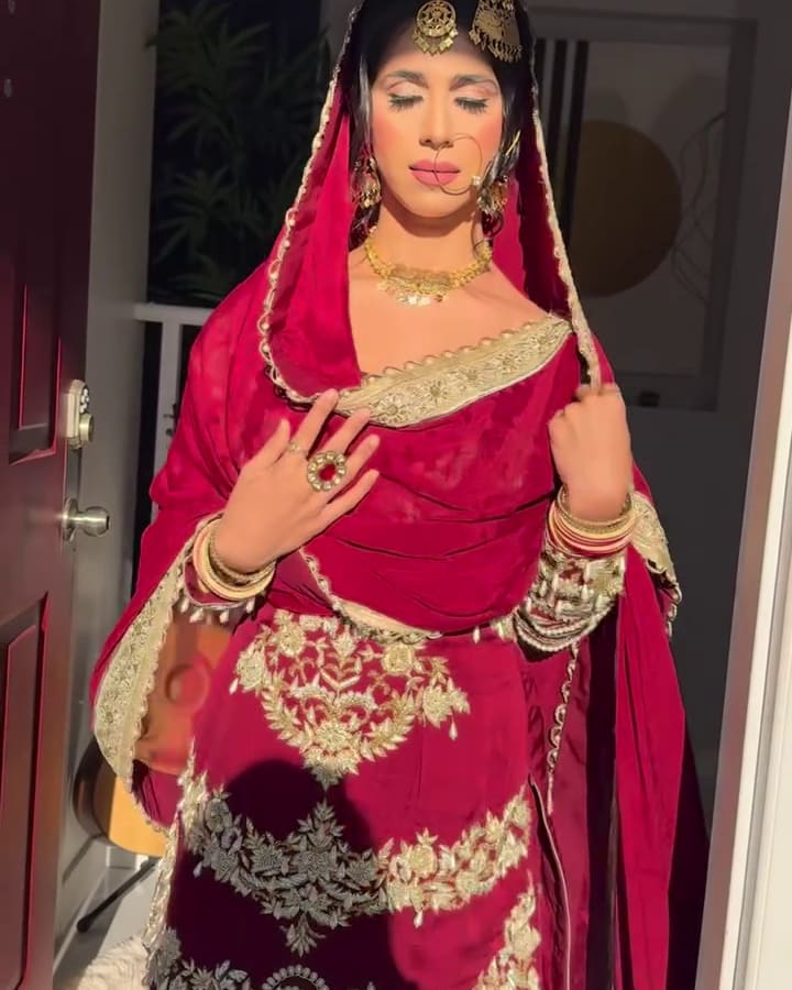 Bride in red with a gold bordered dupatta and gold maang tikka