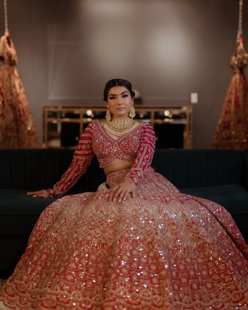 Woman seated in a coral sequin lehenga in a softly lit room