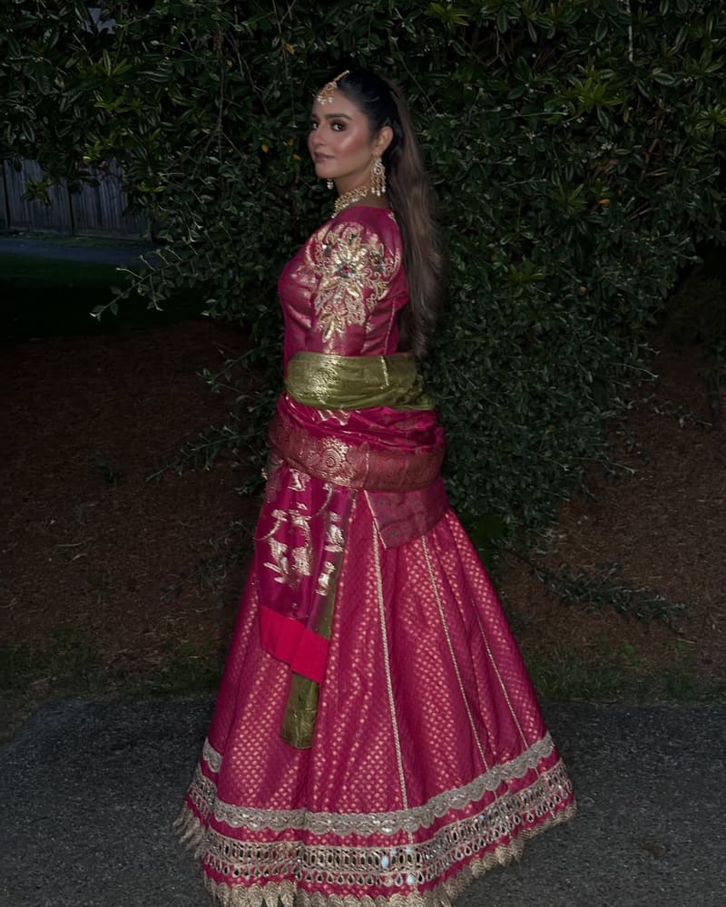 Side view of a fuchsia lehenga with a full flared skirt photographed at night