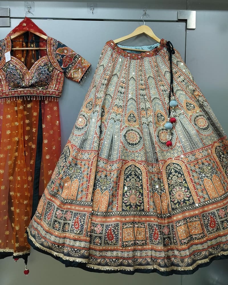 Two lehengas laid out side by side in the boutique, one rust and one pastel with a woven border
