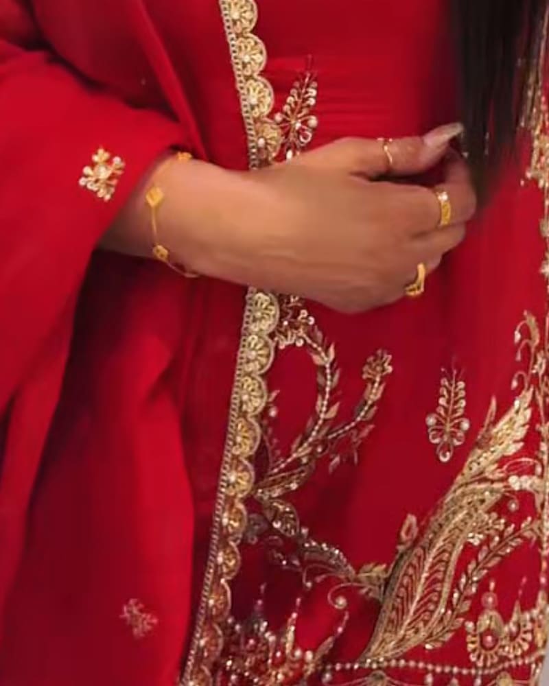 A client wearing her custom order red designer suit with gold embroidery